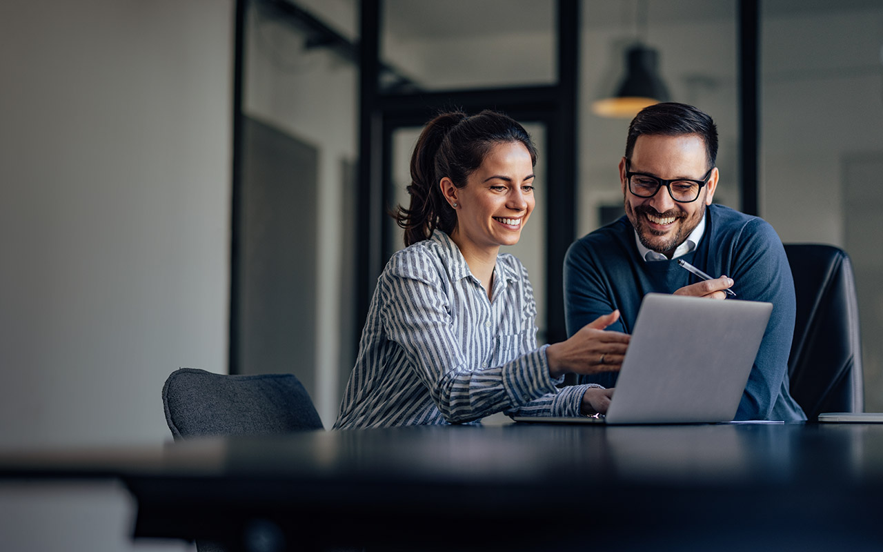 Man and woman in office discussing in front of a computer