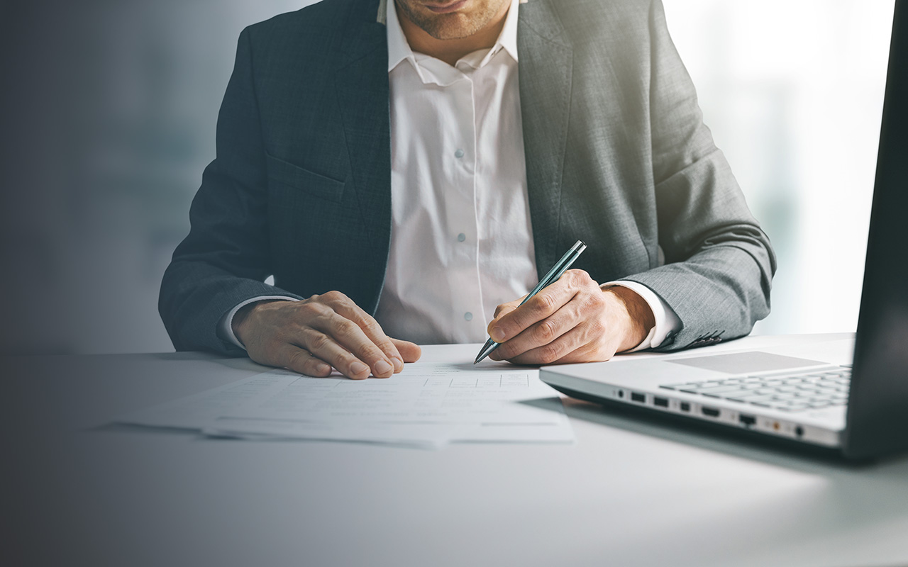 Man in office writing in front of computer