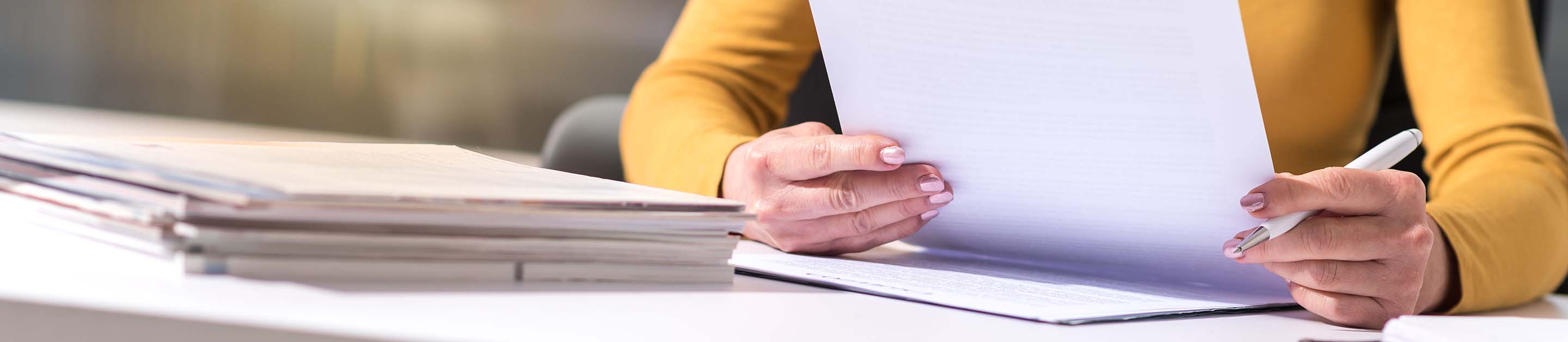 a women sitting on a desk reading a document
