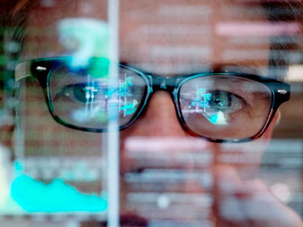 a guy with glasses looking at data on a screen
