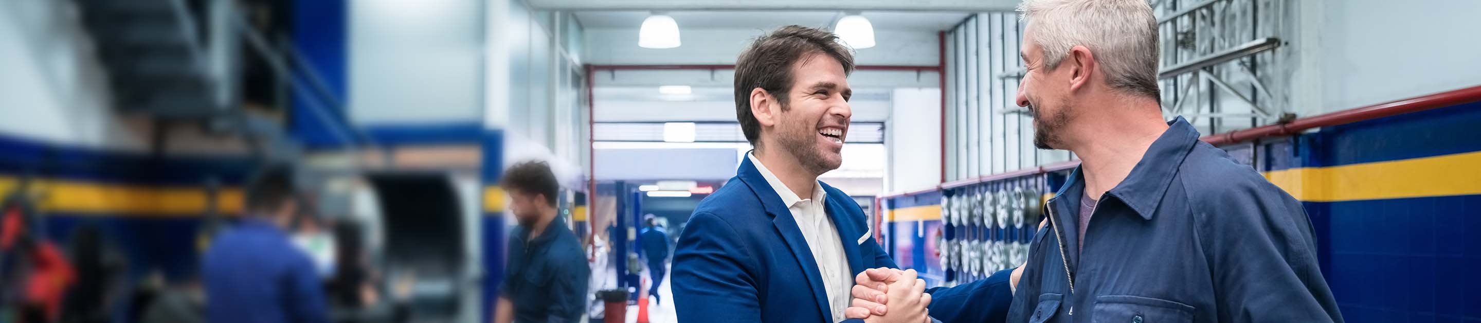 a mechanic and a business man shaking hands smiling