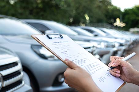 a person with a clipboard with cars parked in the background