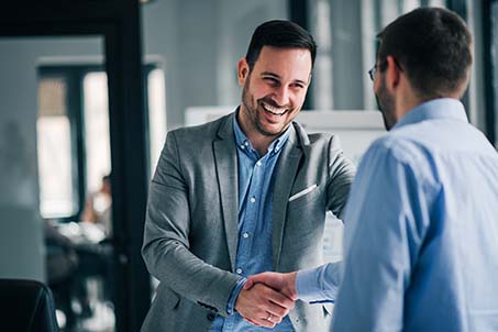 business men shaking hands and smiling at each other 