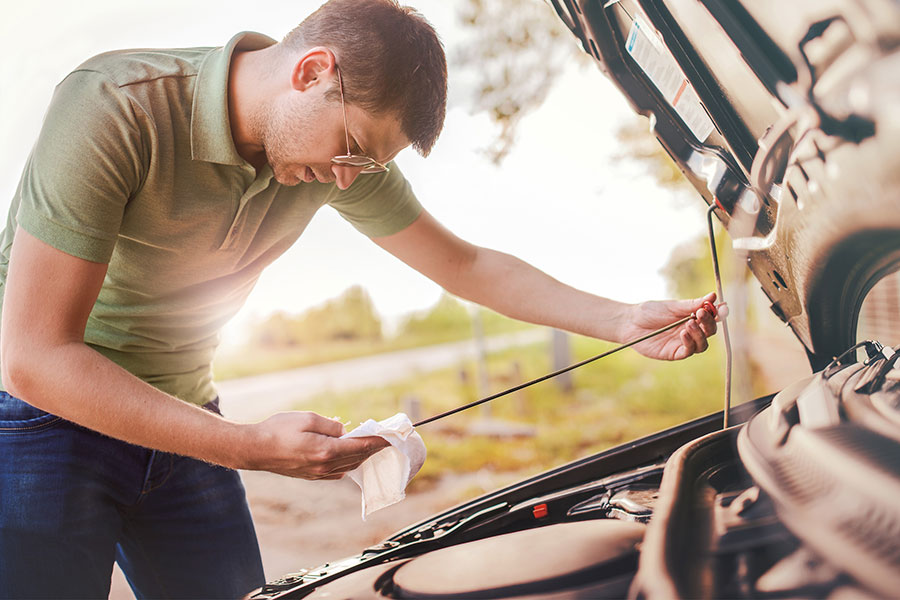 a man looking at his oil levels in an engine