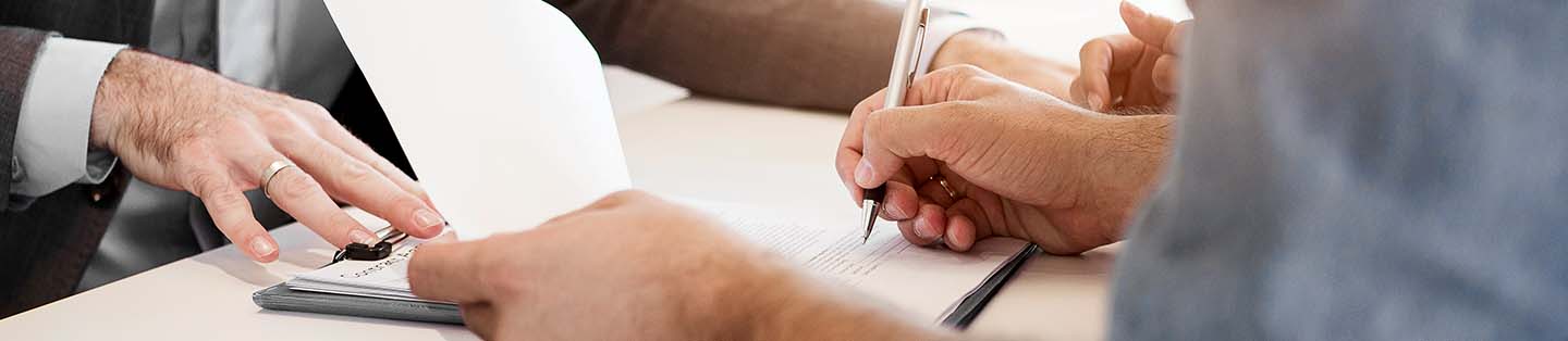 a guy signing documents on a table 